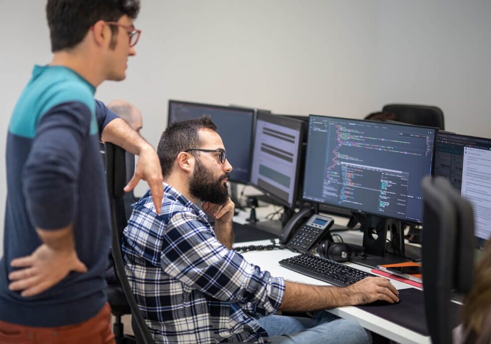 Desarrollador de La Teva Web programando una aplicación a medida con varios monitores